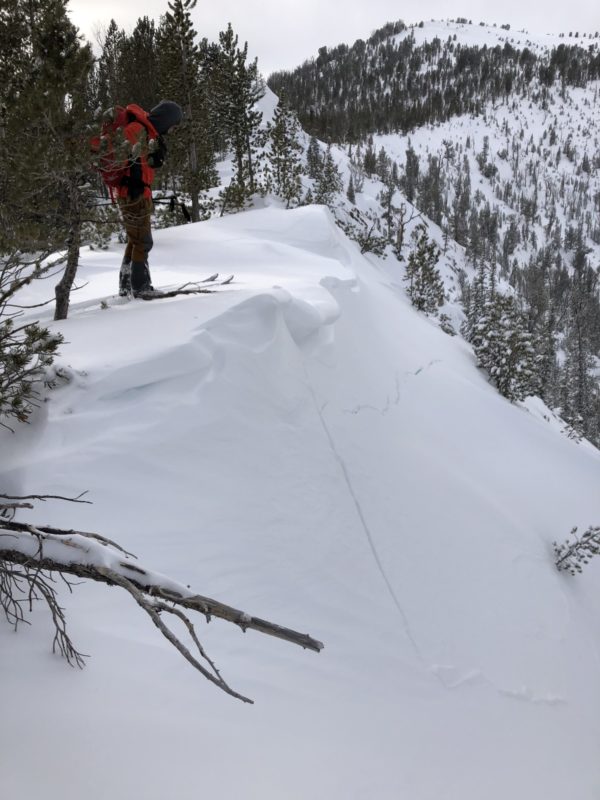 Ben looking down on some cracks that formed from a cornice collapse.